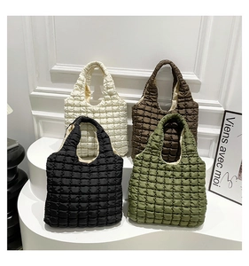 Detailed close-up showing four colors of soft quilted bubble tote bags on white pedestals