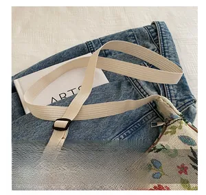 Close-up of adjustable strap and colorful floral embroidery on canvas shoulder bag
