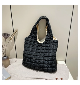 Detail of black quilted puffer tote bag showing soft nylon texture and interior lining