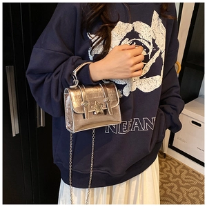 Detail view of the mini silver metallic handbag with star buckle and chain strap on a model