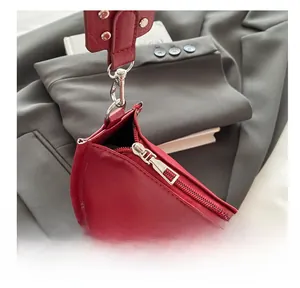 Détail de la fermeture éclair argentée et de la texture en cuir rouge mat du sac