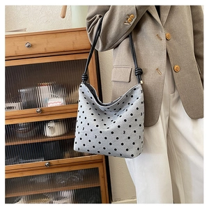 Detailed view of gray polka dot canvas tote bag with black straps on a casual outfit