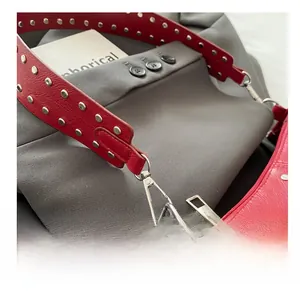 Détail de la bandoulière en cuir rouge avec rivets argentés et mousquetons en métal