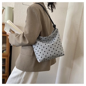 Detailed view of the large gray canvas tote bag with black polka dots on a shoulder strap