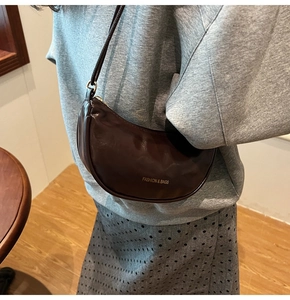 Detail of dark brown leather crescent bag with golden Fashion & Bags logo lettering
