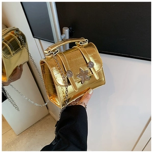 Detail of glossy gold textured leather mini bag with star buckle and chain strap