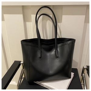 Detail showing the reinforced stitching and fine leather texture of the black tote bag