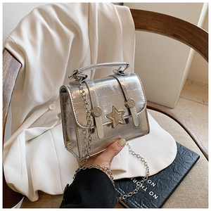 Detail of silver metallic handbag featuring star ornament and chain strap on white blazer