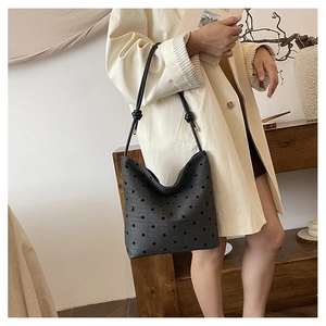 Chic dark grey polka dot canvas tote bag styled on model with minimalist knot strap