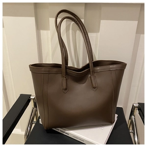 Detail of a large dark brown PU leather tote bag with vertical stitching for work