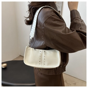 Détail du sac sous l'aisselle blanc avec rivets argentés et bandoulière à rivets