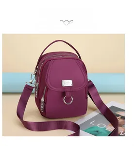 Detailed view of purple nylon mobile phone bag with multiple zipper layers and shoulder strap