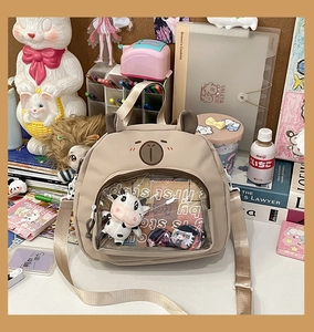 Detail of beige bear ita bag with transparent front pocket for displaying dolls and cards