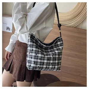 Detailed close-up of checkered canvas tote bag with black bow embroidery accents