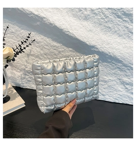 Dettaglio di pochette trapuntata argento con texture metallica in ecopelle lucida