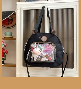 Detail of a black canvas crossbody bag featuring a cute bear shape and clear window pocket