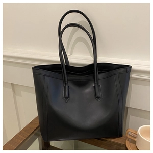 Close-up of a large black vintage tote bag on a wooden bench with coffee accessories