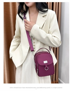 Close-up of a purple nylon mini crossbody bag with multiple layers and silver metal hardware