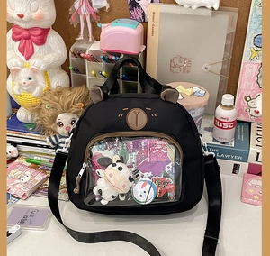 Detail of a black cartoon bear Ita Bag with transparent PVC window and plush charms