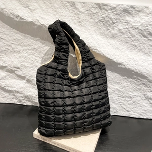 Fashionable black quilted puffy cloud tote bag with lightweight fabric on a white surface