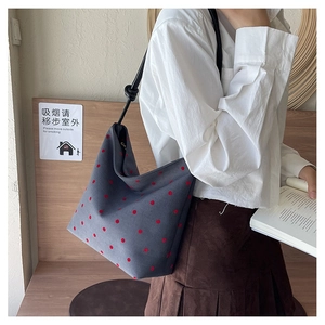 Close-up of gray canvas tote bag with red polka dots and black knotted rope straps