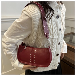 Detail einer Vintage-Achseltasche in Rotbraun mit Silbernieten und breitem Riemen