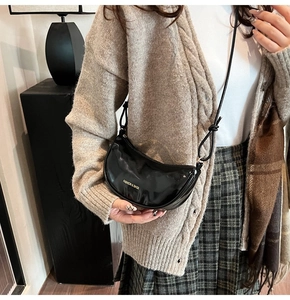 Detail of black glossy half-moon crossbody bag with golden Fashion & Bags logo lettering