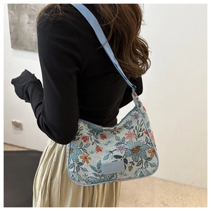 Detail of light blue floral jacquard shoulder bag with brand logo and webbed strap