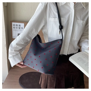 Detail view of grey canvas tote bag with red polka dots and knotted black shoulder strap