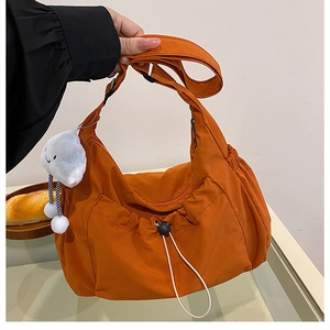 Detail of orange nylon crossbody bag with adjustable drawstring and plush cloud charm