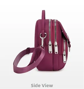 Detailed side view of multi-layer magenta nylon crossbody bag with three silver zippers