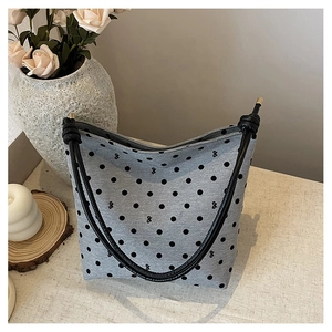 Detail of grey polka dot tote bag with knotted black straps and gold hardware caps