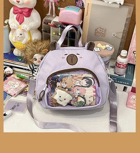 Detail of purple bear-shaped clear window bag showing anime pins and accessories