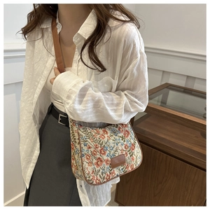Close-up of vintage floral pattern canvas handbag with premium brown leather trim and strap