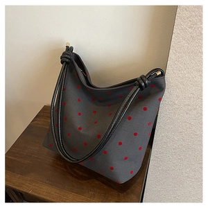 Detail of grey canvas tote bag with red polka dots and knotted black shoulder strap