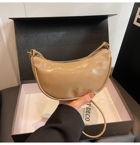 Detail of beige half-moon shoulder bag with golden logo and elegant gift box