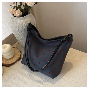 Macro detail of canvas shoulder bag with red polka dots and black woven rope handle