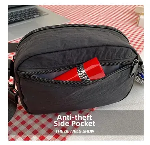 Detail of a black nylon crossbody bag featuring an anti-theft side pocket for small items