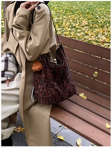 Macro shot of stylish leopard print tote bag with brown plush bear charm accessory