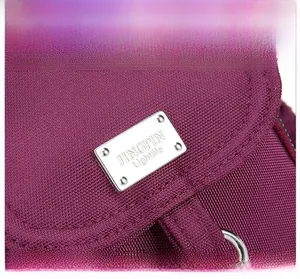 Close-up of silver metal logo plate on purple textured nylon fabric of the crossbody bag