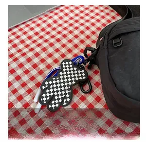 Detail of checkered bear pendant with blue lanyard and metal carabiner on nylon bag
