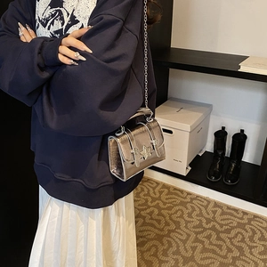 Silver metallic crossbody bag with star hardware and chain strap on a model