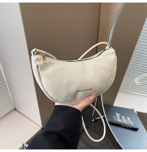 Detail of white crescent moon bag showing fine leather texture and fashion logo lettering