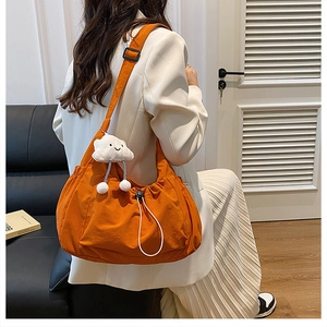 Orange nylon drawstring shoulder bag shown with a cute white cloud plush pendant accessory