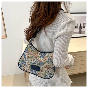 Close-up of floral jacquard shoulder bag with blue leather trim and embossed brand tag