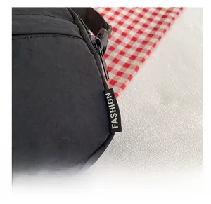 Detail shot of durable black nylon crossbody bag with fashion label and metal zipper