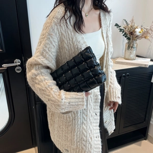 Elegante borsa da toilette trapuntata nera da donna abbinata a un cardigan in maglia