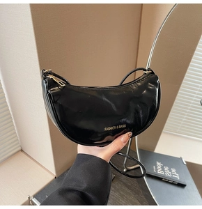 Detail of black glossy crinkle patent leather texture on chic crescent shoulder bag