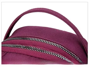 Detailed macro view of purple nylon fabric bag featuring durable handle and metal zippers
