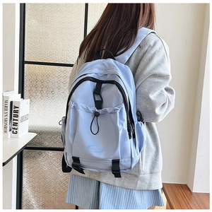 Detail view of the light blue nylon backpack showing functional pockets and drawstring